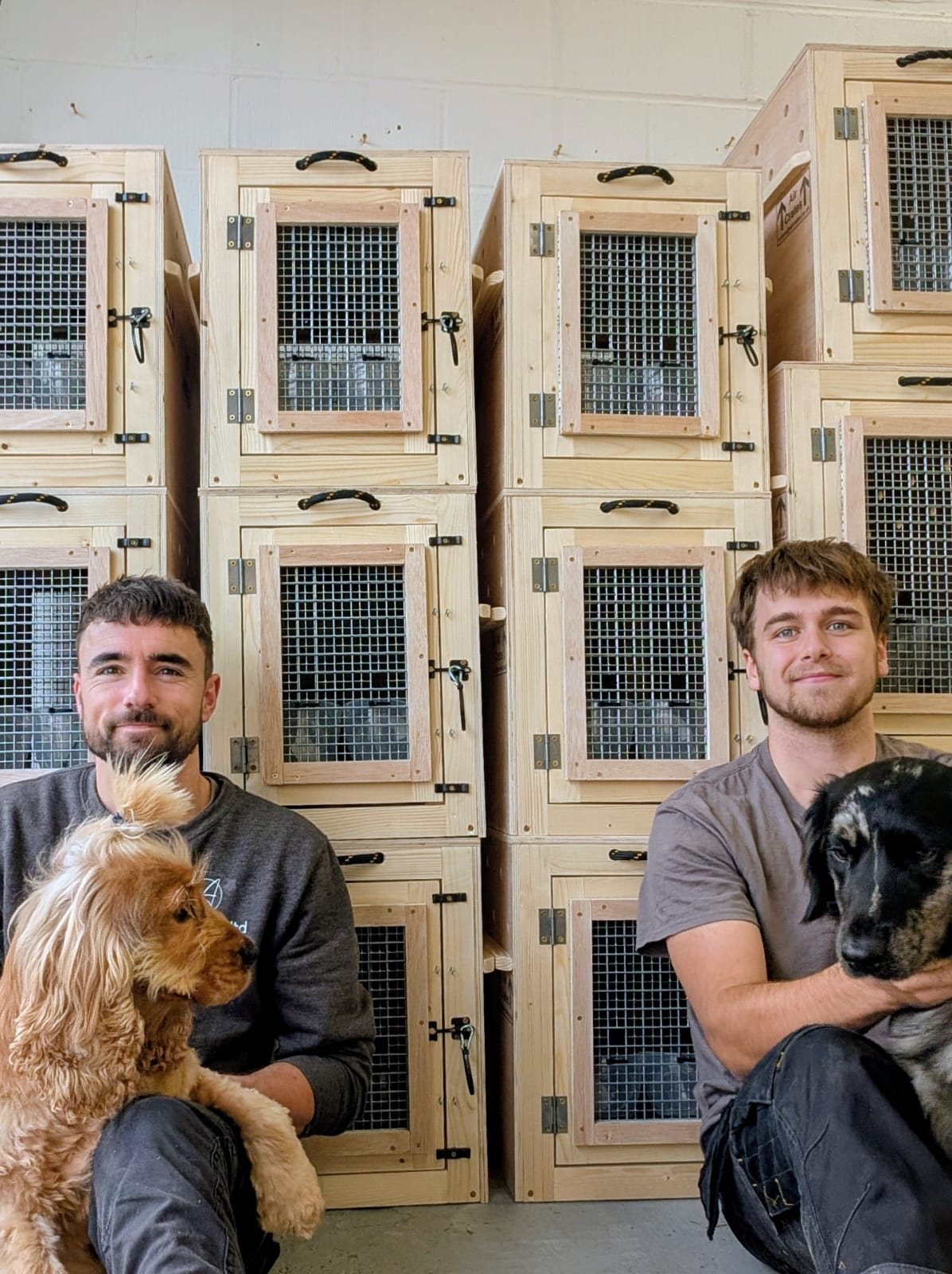 The Air Crates makers with two of the workshop dogs, in front of a batch of finished crates